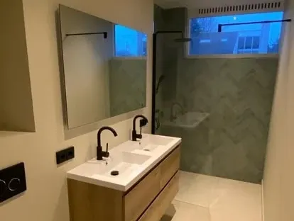 Badkamerrenovatie met zorgvuldig afgestemd sanitair, tegelwerk en verlichting.