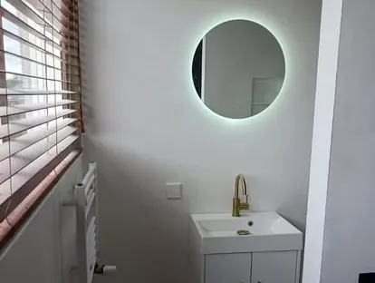 Badkamerrenovatie met zorgvuldig afgestemd sanitair, tegelwerk en verlichting.