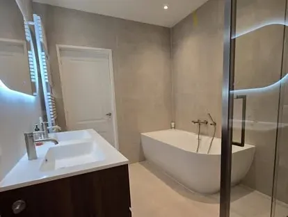 Badkamerrenovatie met zorgvuldig afgestemd sanitair, tegelwerk en verlichting.