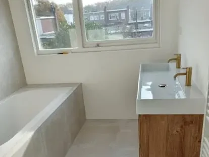 Maatwerk sanitair en tegelwerk in een gerenoveerde badkamer.