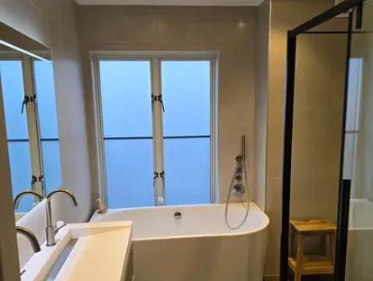 Badkamerrenovatie met zorgvuldig afgestemd sanitair, tegelwerk en verlichting.