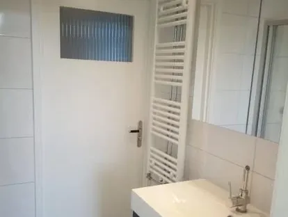 Badkamerrenovatie met zorgvuldig afgestemd sanitair, tegelwerk en verlichting.