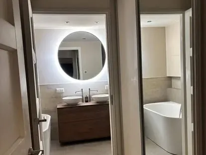 Badkamerrenovatie met zorgvuldig afgestemd sanitair, tegelwerk en verlichting.