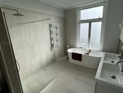 Badkamerrenovatie met zorgvuldig afgestemd sanitair, tegelwerk en verlichting.