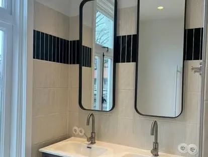 Badkamerrenovatie met zorgvuldig afgestemd sanitair, tegelwerk en verlichting.