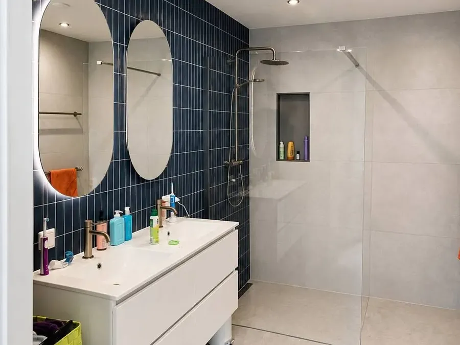 Badkamerrenovatie met zorgvuldig afgestemd sanitair, tegelwerk en verlichting.