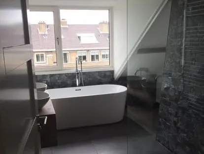 Badkamerrenovatie met zorgvuldig afgestemd sanitair, tegelwerk en verlichting.