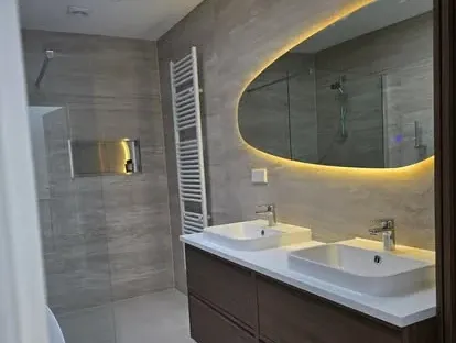 Badkamerrenovatie met zorgvuldig afgestemd sanitair, tegelwerk en verlichting.