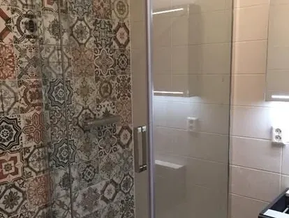 Badkamerrenovatie met zorgvuldig afgestemd sanitair, tegelwerk en verlichting.
