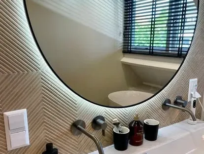 Badkamerrenovatie met zorgvuldig afgestemd sanitair, tegelwerk en verlichting.
