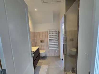Badkamerrenovatie met zorgvuldig afgestemd sanitair, tegelwerk en verlichting.