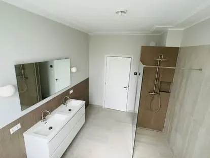 Badkamerrenovatie met zorgvuldig afgestemd sanitair, tegelwerk en verlichting.