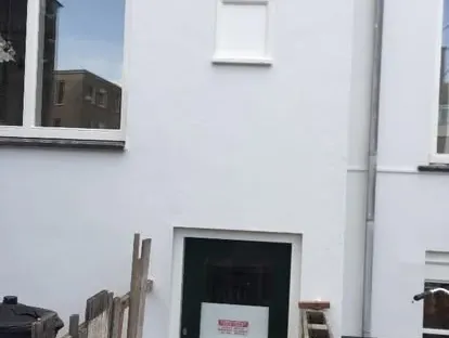 Vernieuwde buitenruimte en gevelafwerking bij een woningrenovatie.